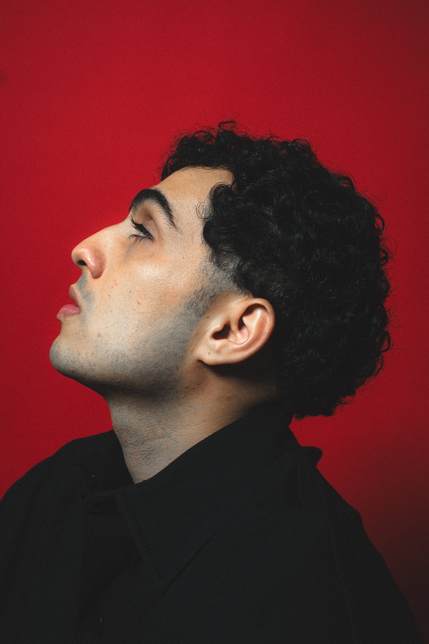 Retrato de perfil, roupa preta, fundo vermelho fotografado
