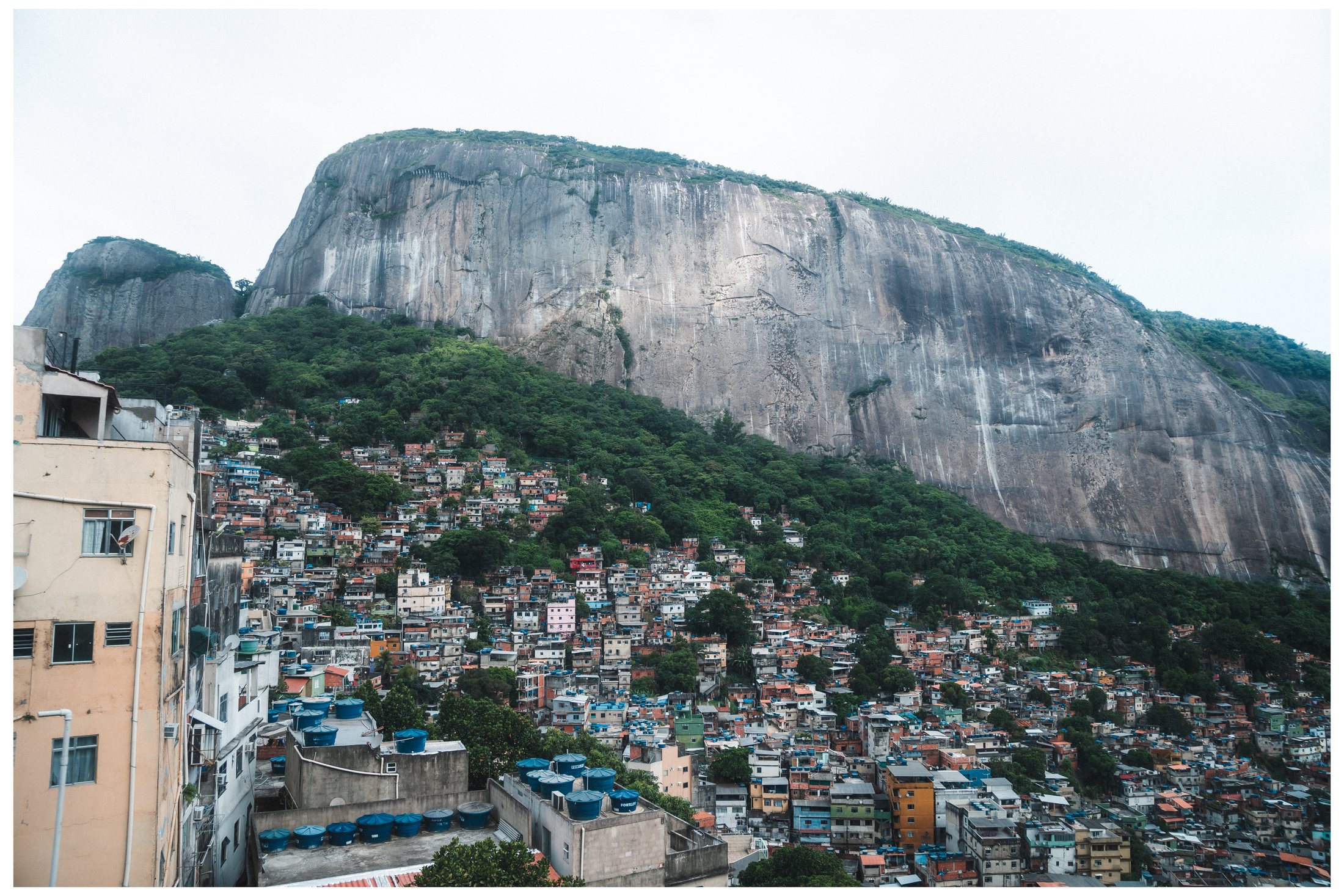Encosta com casas e formação rochosa ao fundo
